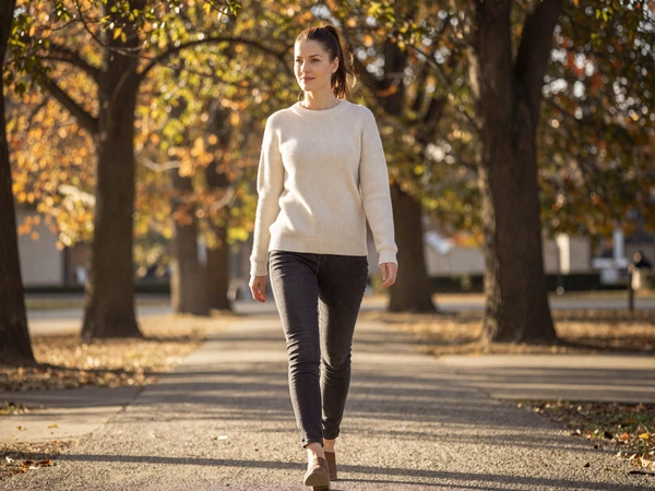 Female nurse midwife in premium casual fashion walking through a sunny park on her day off